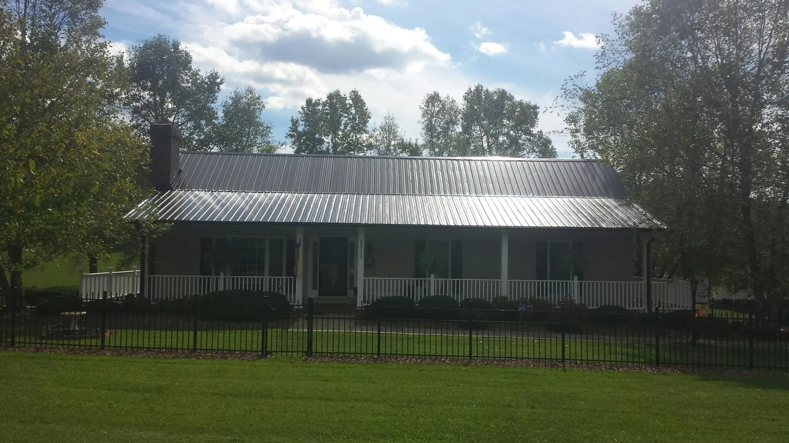 Gray metal roof on a brick ranch with a full width front porch — Gutter Guard Installation work by our crew in Clarksdale