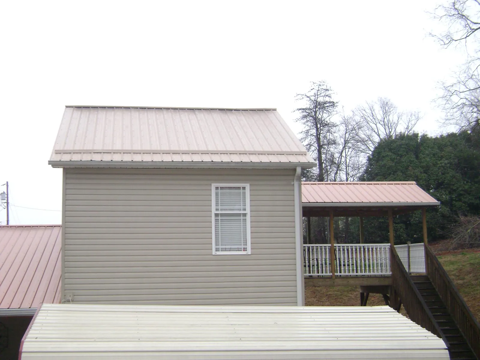 Tan metal roofs on a two story addition and attached porch, from a Roof Replacement job in Clarksdale